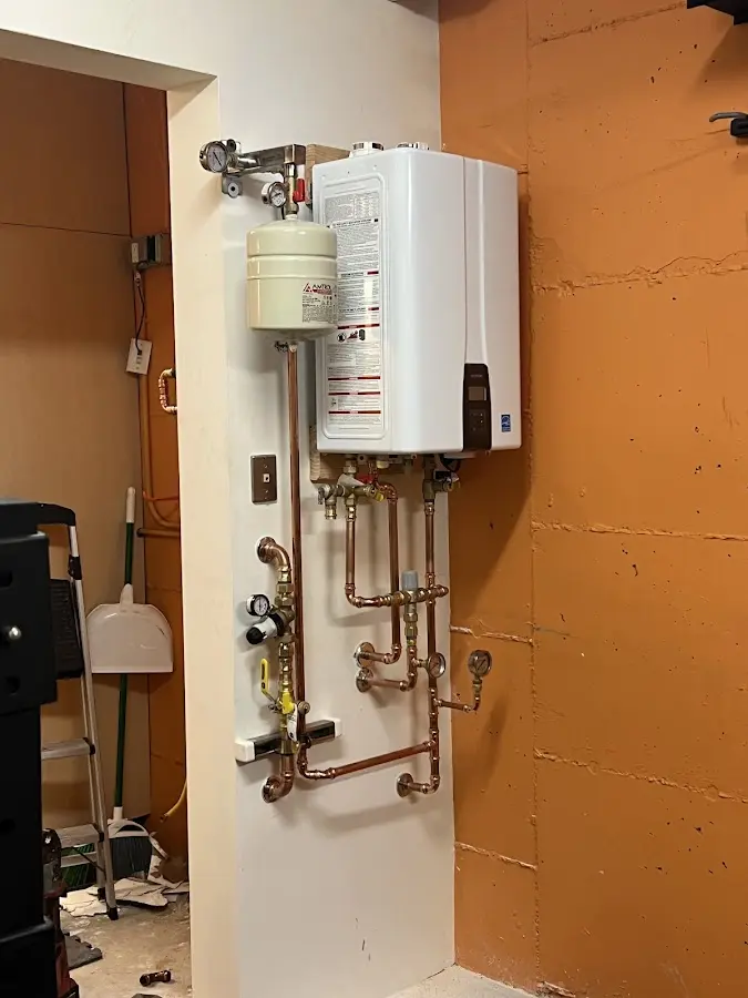 Plumbing technician inspecting water heater connections in Urbandale